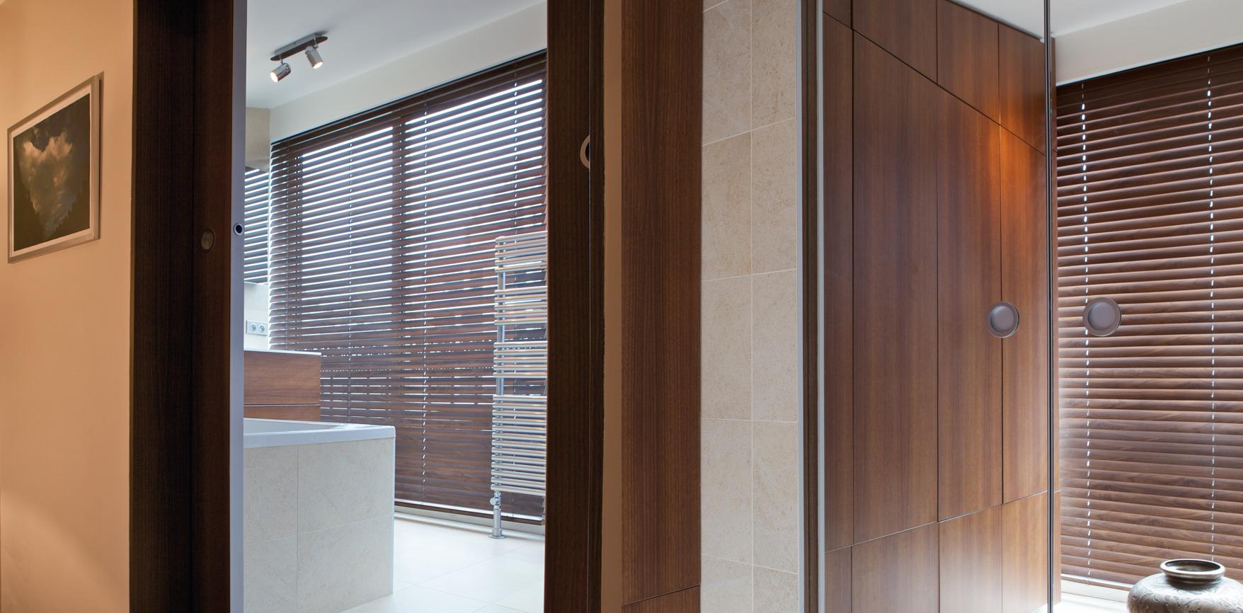 In this master bedroom, wooden blinds on the dressing room and bathroom sides. The advantage : electric blinds.