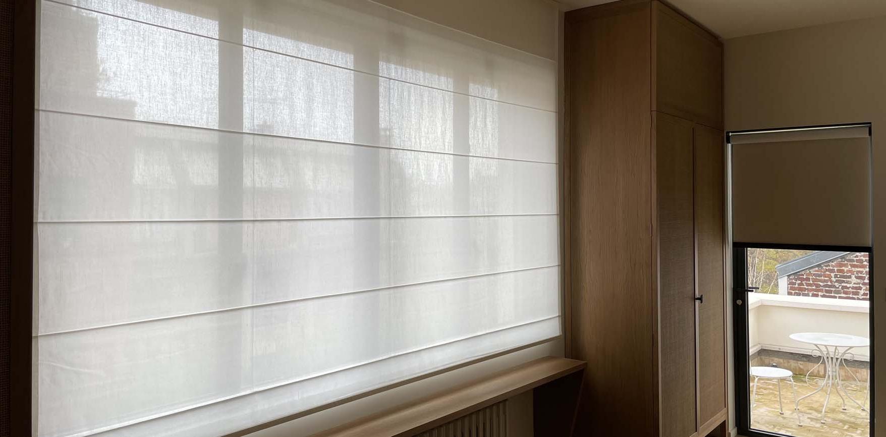 In the master bedroom, a wide roman blind covers the window to filter the view.
