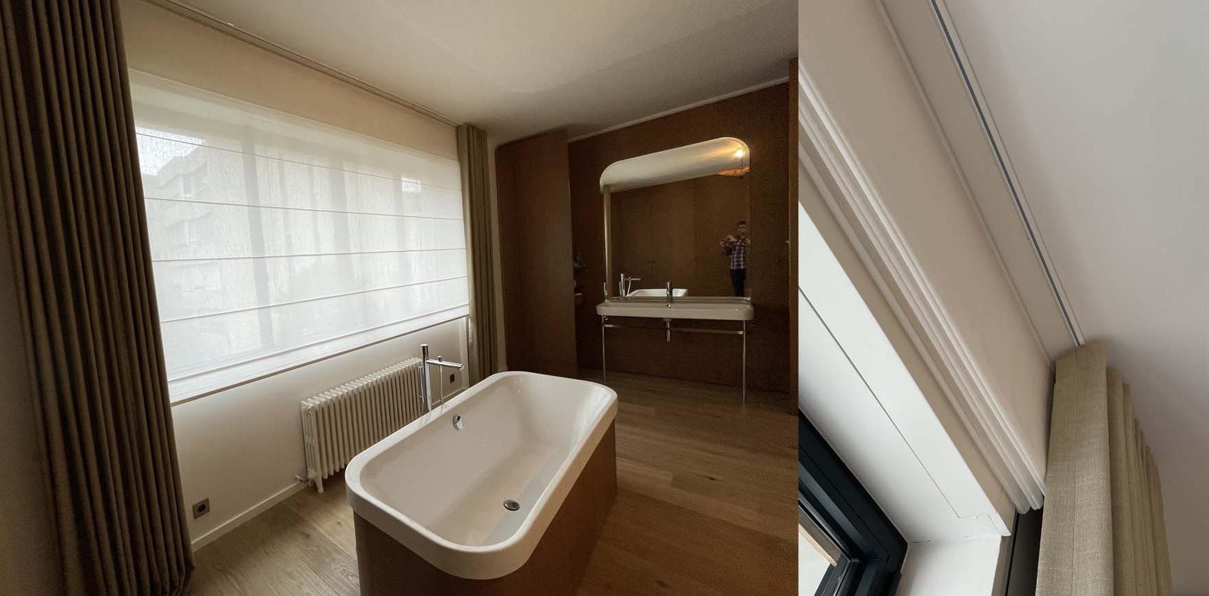 In the main bathroom, the very large window is covered with a roman blind and a pair of curtains.